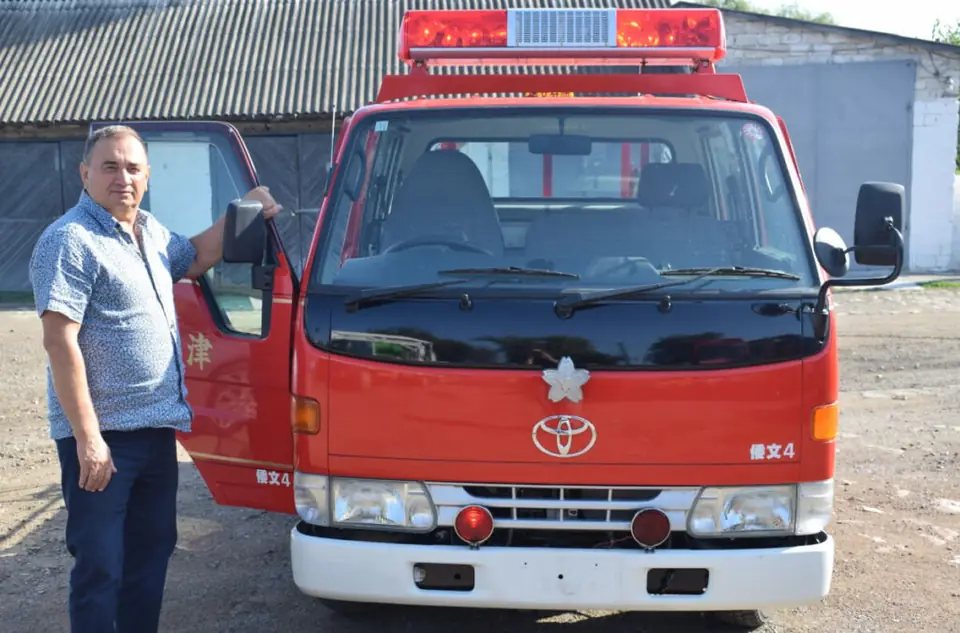 Red Toyota fire engine and local residents welcoming the gift